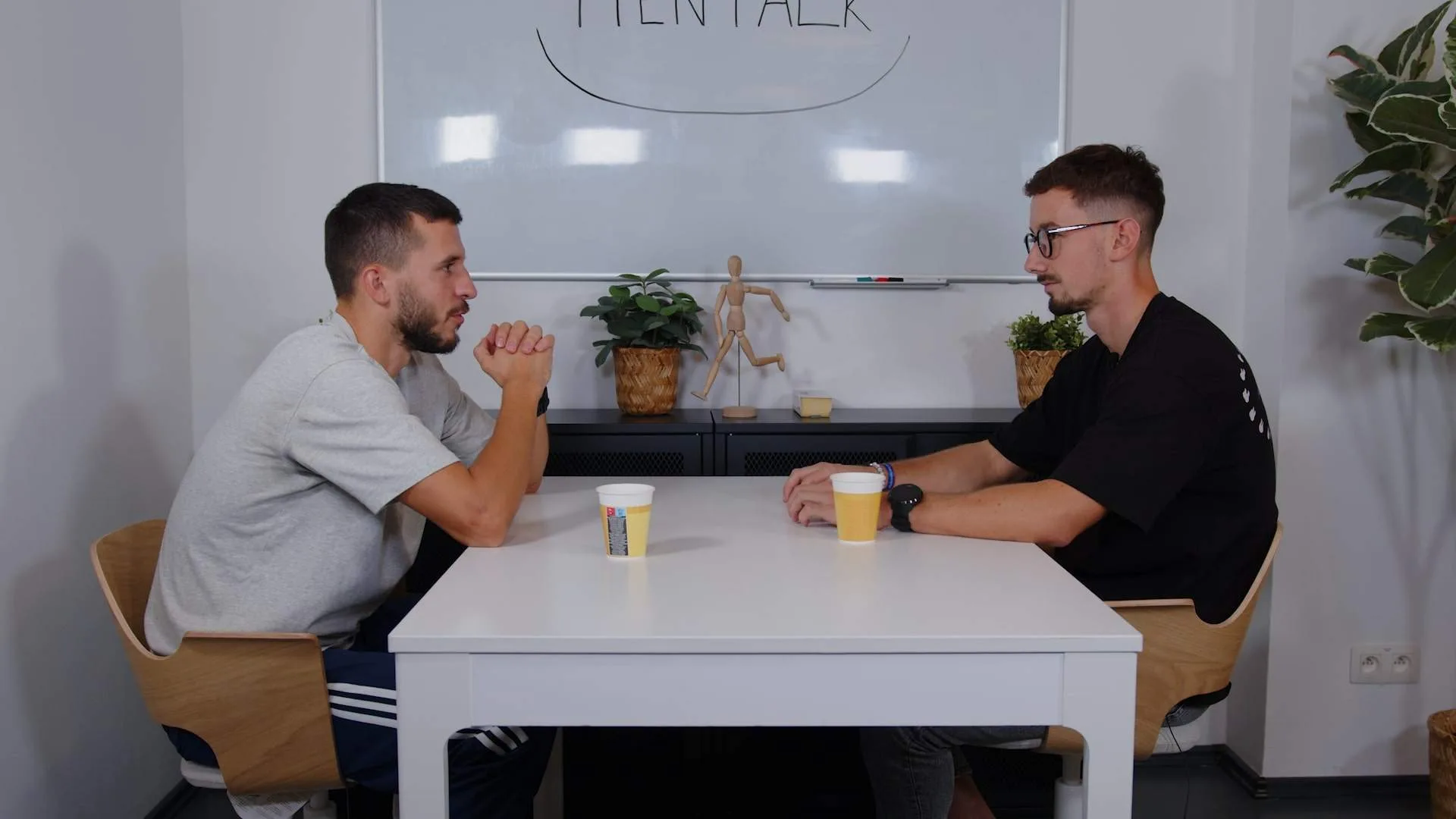 Dvaja hostia podcastu MENTALK pri neformálnom rozhovore v štúdiu s bielou tabuľou