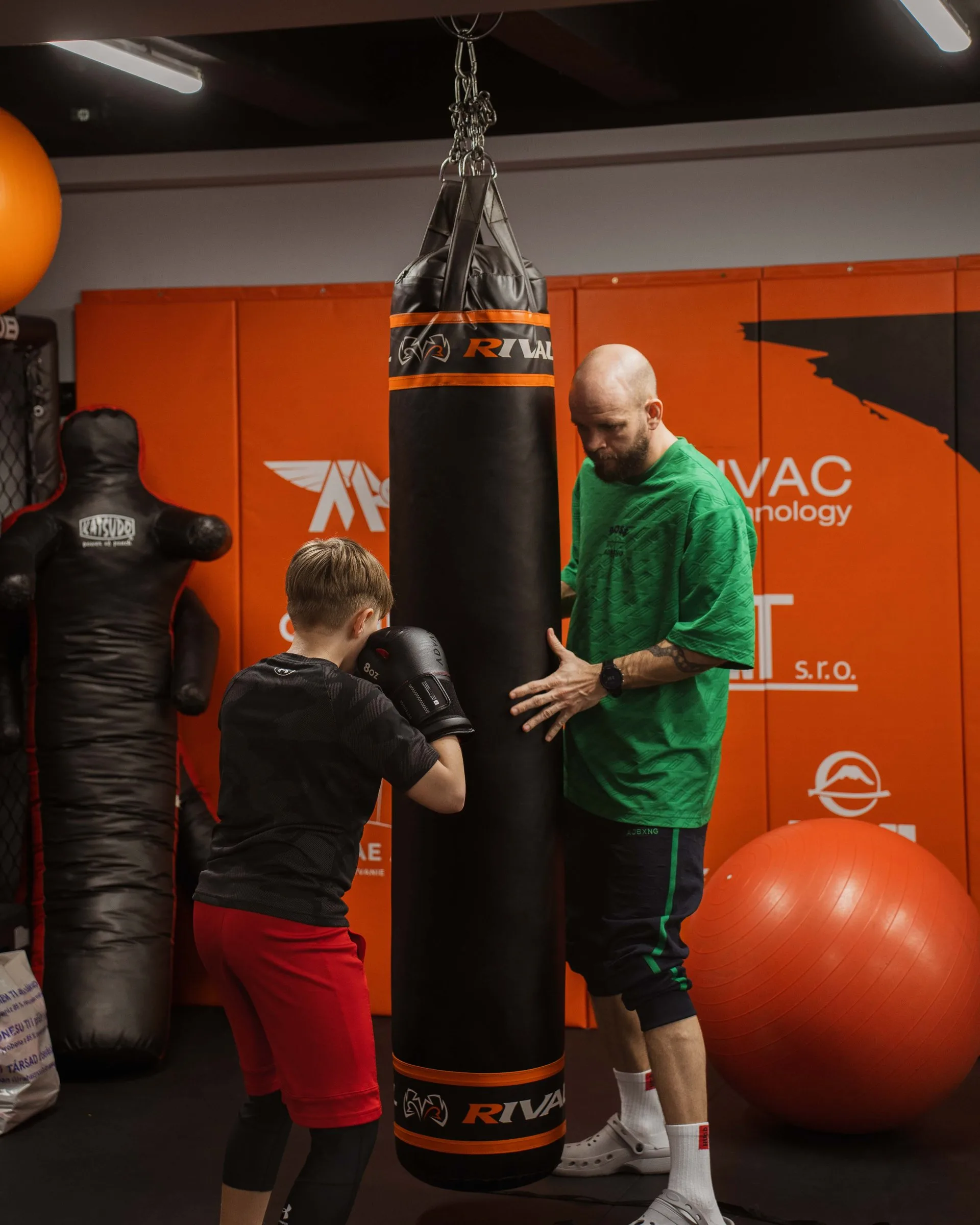 Tréner drží vrece pri tréningu dieťaťa v Legacy Fight Club
